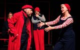 One female stretches her arms out towards a male dressed in a red jacket, hat and scarf.