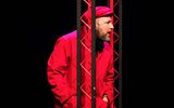 A male dressed in an all red outfit stands against a black background.