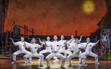 A group of males dance wearing all white outfits.